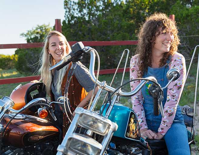 Two woman laughing on motorcycles 